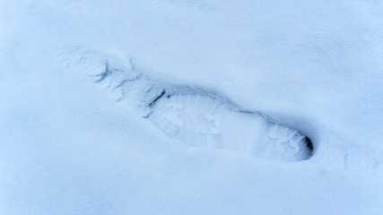 Fototapeta na wymiar One footprint from a male boot in the snow