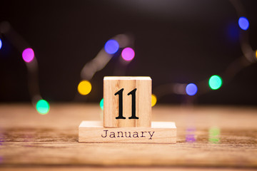 January 11th. Day 11 of month, calendar on dark background with garland bokeh. Winter time, year...