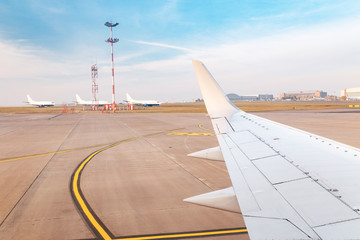 Wing of airplane at the background of taxiway in airport