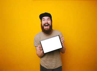 Photo of young bearded man is excited about his new tablet