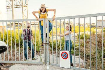 Group of friends having fun and climbing over fence, break the rules concept