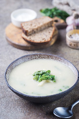 Fresh asparagus cream soup in a bowl over gray stone table