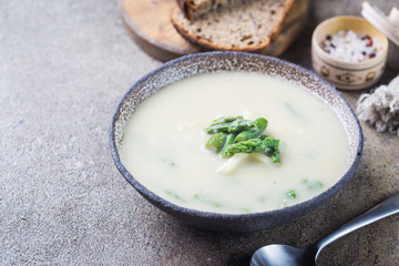 Fresh asparagus cream soup in a bowl over gray stone table