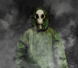 Man in gas mask and USSR cloak of chemical protection surrounded by smoke