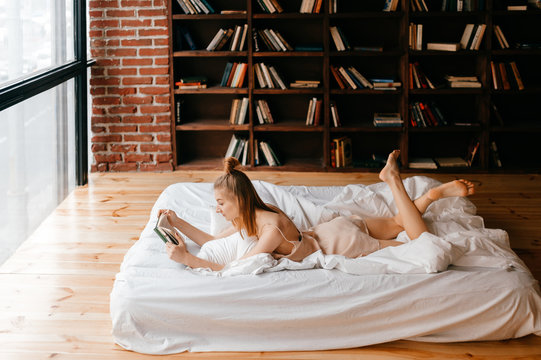 Young girl in negligee reading book in bed