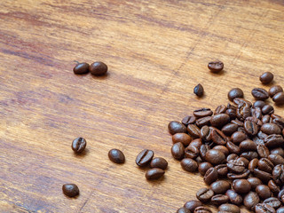 Heap of roasted coffee beans on wood background, macro, copy space