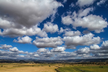 Fototapeta premium Clear sky with natural colors of an intense Mediterranean blue and white clouds on a plain of typical Sardinian vegetation