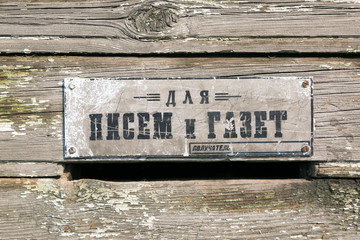 Old hole in the wall for paper mail. A slot in the wooden wall of the house for the delivery of letters of mail and documents to the subscriber.