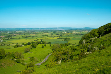 Extensive view towards the River Severn and The Forest of Dean over a patchwork of fields with a winding road in the foreground, Coaley Peak Picnic Site and Viewpoint, Gloucestershire, UK