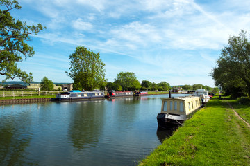 Obraz premium Spring sunshine on boats moored by St Marys Church on the Gloucester & Sharpness Canal, Frampton on Severn, Gloucestershire, UK