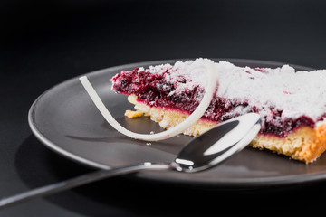 Close-up piece of cherry pie sprinkled with powdered sugar on a plate