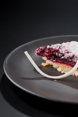 Close-up piece of cherry pie sprinkled with powdered sugar on a plate