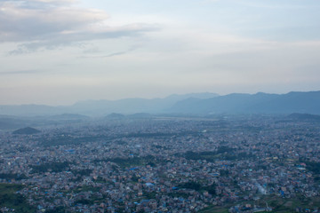 view of the huge city valley on the background of the silhouette of the mountains in the evening under heavy sky