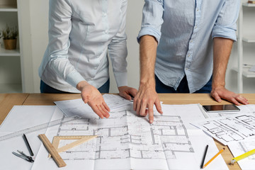 Cropped two partners specialist builder person in formalwear shirt stand in loft interior workstation hold pencil in hand indicate look at graphic make brainstorming renovation room in structure