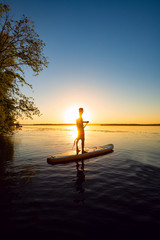 Silhouette of man who is paddling on a SUP board