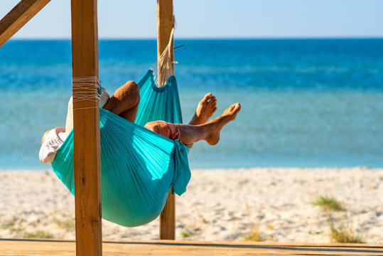 Man relaxes in a hammock on abandoned bungalow veranda