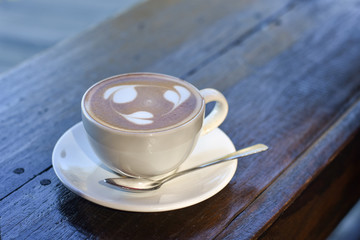 Cup of coffee on wooden table. Latte coffee with latte art of three tree leaves.