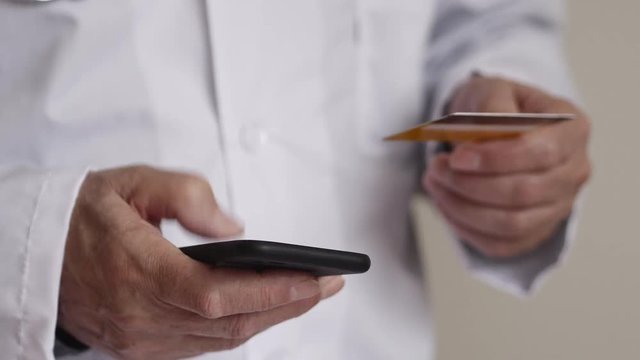 Doctor Using Mobile Phone With Credit Card