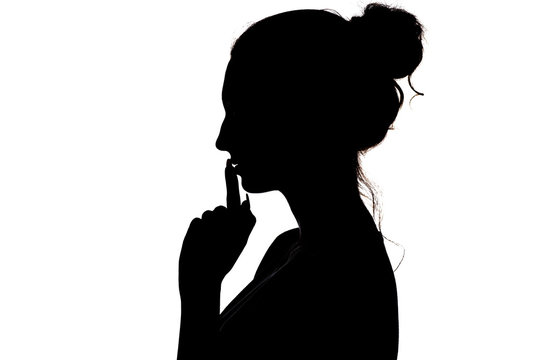 young woman making a sign by finger near lips that means silence or secret, silhouette profile of unknown girl with a bun, privacy concept