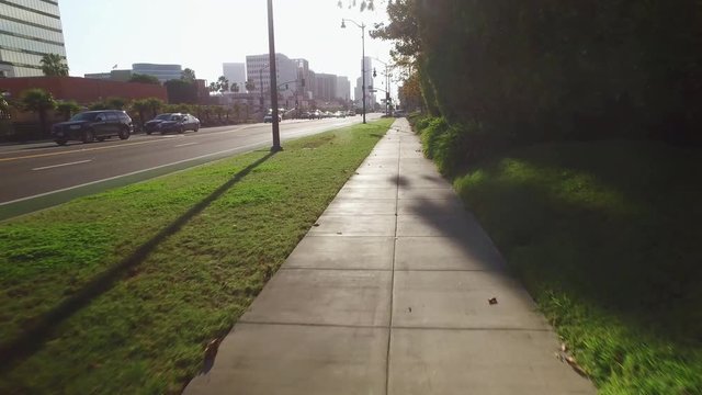 A low angle walking perspective on a Beverly Hills sidewalk near Wilshire Boulevard.  	