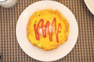 Omelet with shrimp on top served in white plate