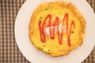 Omelet with shrimp on top served in white plate