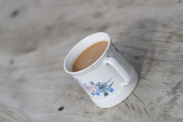 Cup of coffee on grunge wood table in morning sunlight