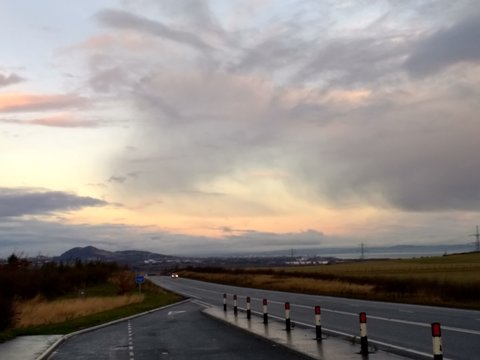 Beautiful sweeping dramatic landscape view of highway road and cloudy sunset sky in December travelling by car on the drive from Gifford in East Lothian towards Edinburgh