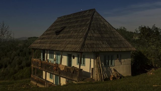 Old romanian country house in Apuseni Mountains at summer night with stars. Time lapse with long exposure.