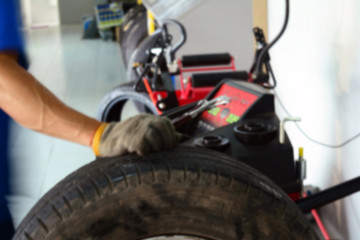 Obraz premium the blur of the mechanic install the wheel with the tyre balancing machine before test