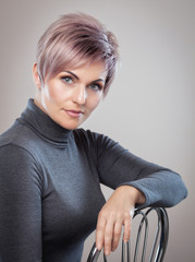 Portrait of a beautiful blonde woman with beautiful make-up and short haircut after dyeing hair in a hairdressing salon. © Dimid
