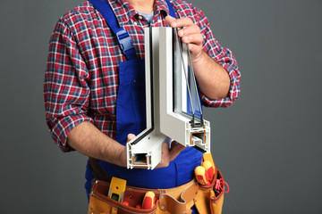 Installation worker with sample of modern window profile on gray background