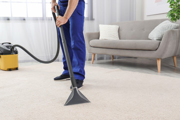 Man removing dirt from carpet with vacuum cleaner indoors, closeup. Space for text