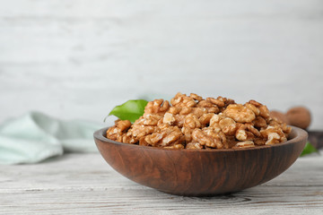 Plate with tasty walnuts on wooden table