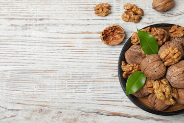 Plate with walnuts and space for text on wooden background, top view