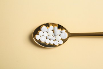 Spoon of pills on color background, top view