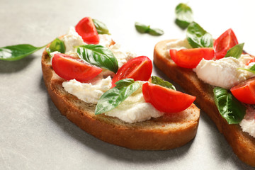 Toasted bread with tasty cream cheese and tomatoes on gray table