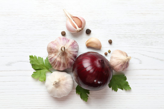 Composition with garlic, parsley and onion on white wooden background, top view