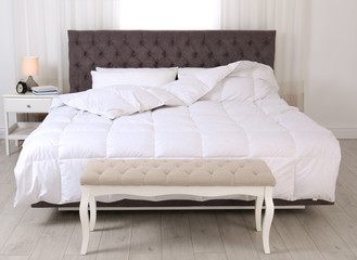 Fototapeta na wymiar Large comfortable bed in light room. Stylish interior