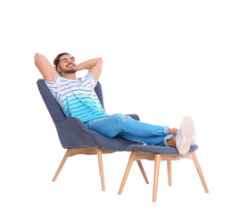 Handsome young man relaxing in armchair with legs on footrest against white background