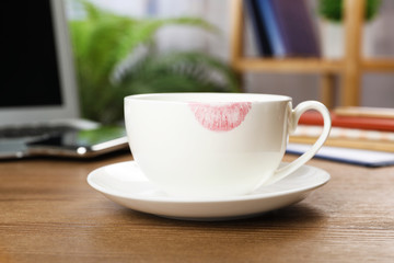 Ceramic cup with lipstick mark on table at workplace