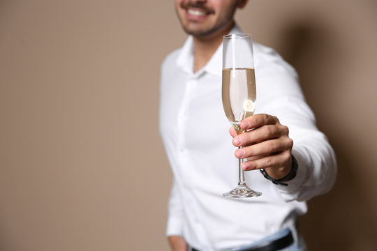 Handsome man with glass of champagne on color background, closeup. Space for text