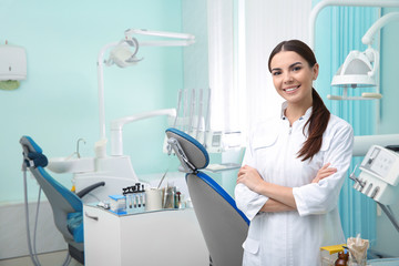 Jonge vrouwelijke tandarts in witte jas op de werkplek. Ruimte voor tekst