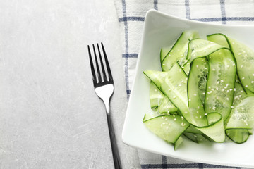 Plate with delicious cucumber salad served on grey table, top view. Space for text