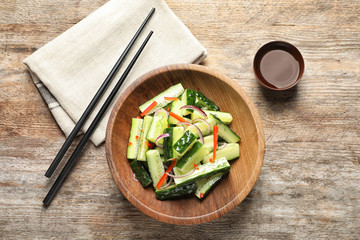 Plate with delicious cucumber salad served on wooden table, top view