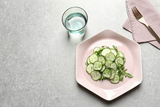 Plate with delicious cucumber salad served on grey table, top view. Space for text