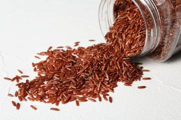 Pile of brown rice and jar on table, closeup