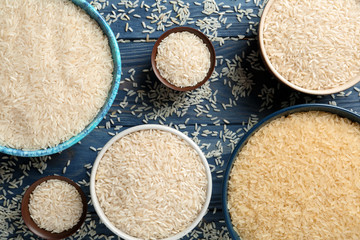 Flat lay composition with different types of rice in bowls on color wooden background