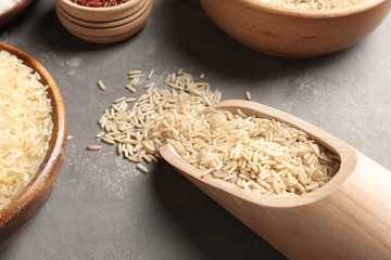 Brown and other types of rice on grey table, closeup view
