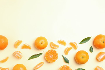 Composition with tangerines and leaves on color background, flat lay. Space for text